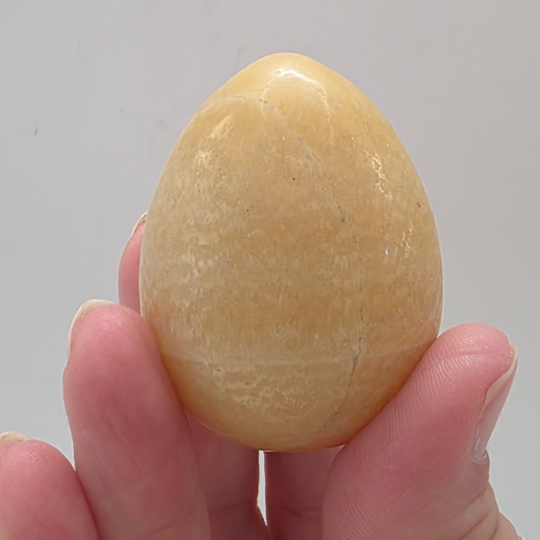 Close up of orange calcite egg showing polished finish and vibrant orange colour