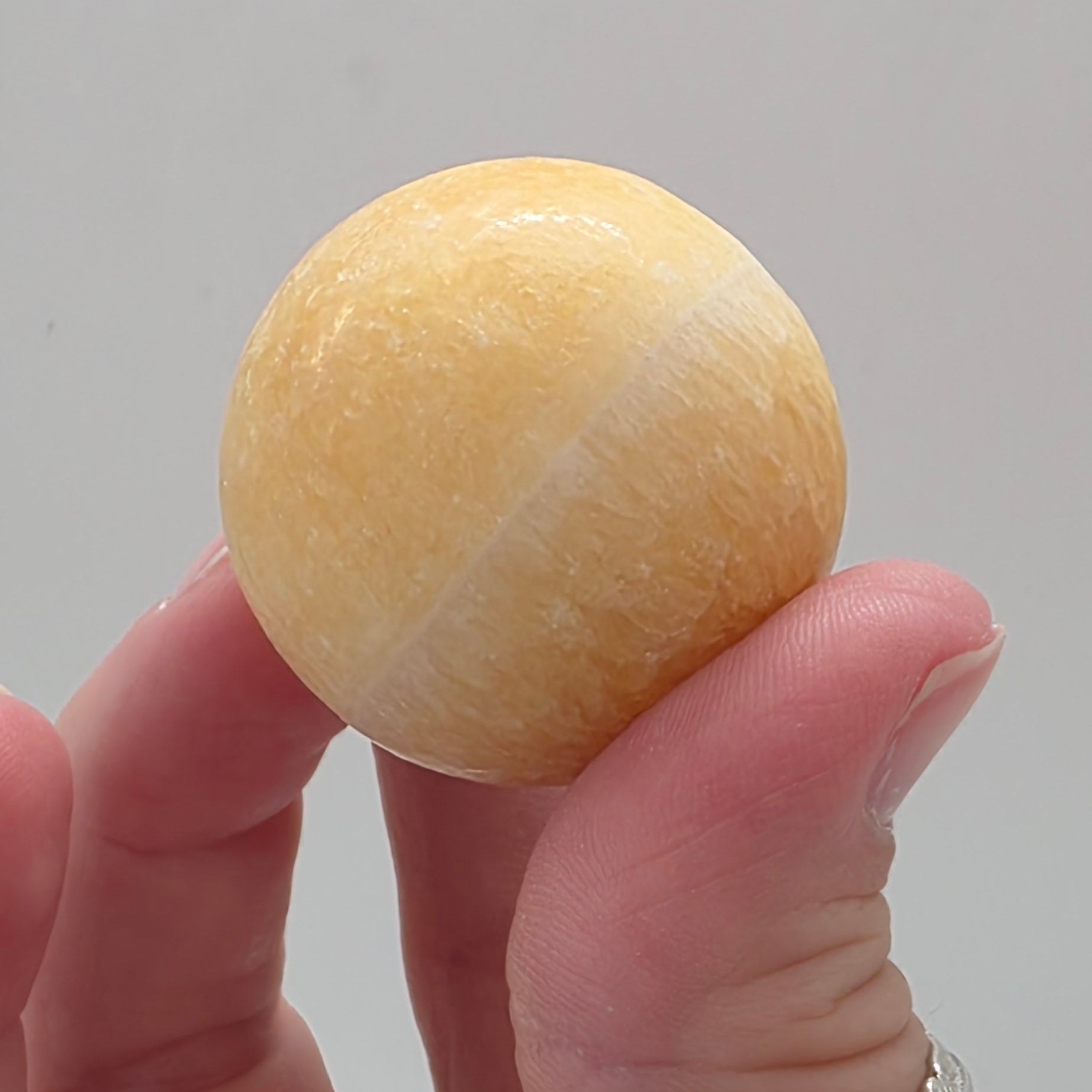 Close up of orange calcite sphere showing natural matte texture – characteristic of calcite
