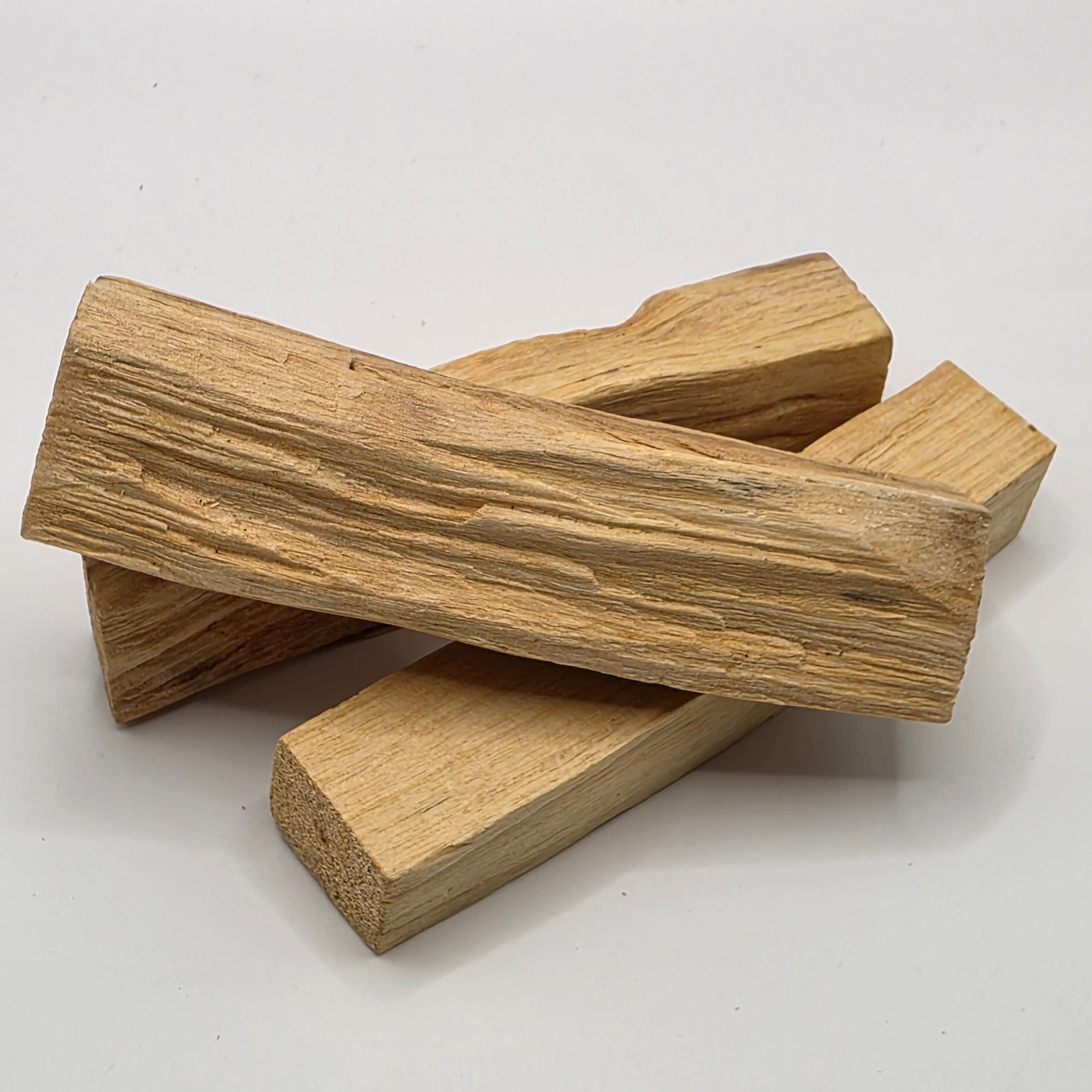Three wooden palo santo sticks stacked on a white background
