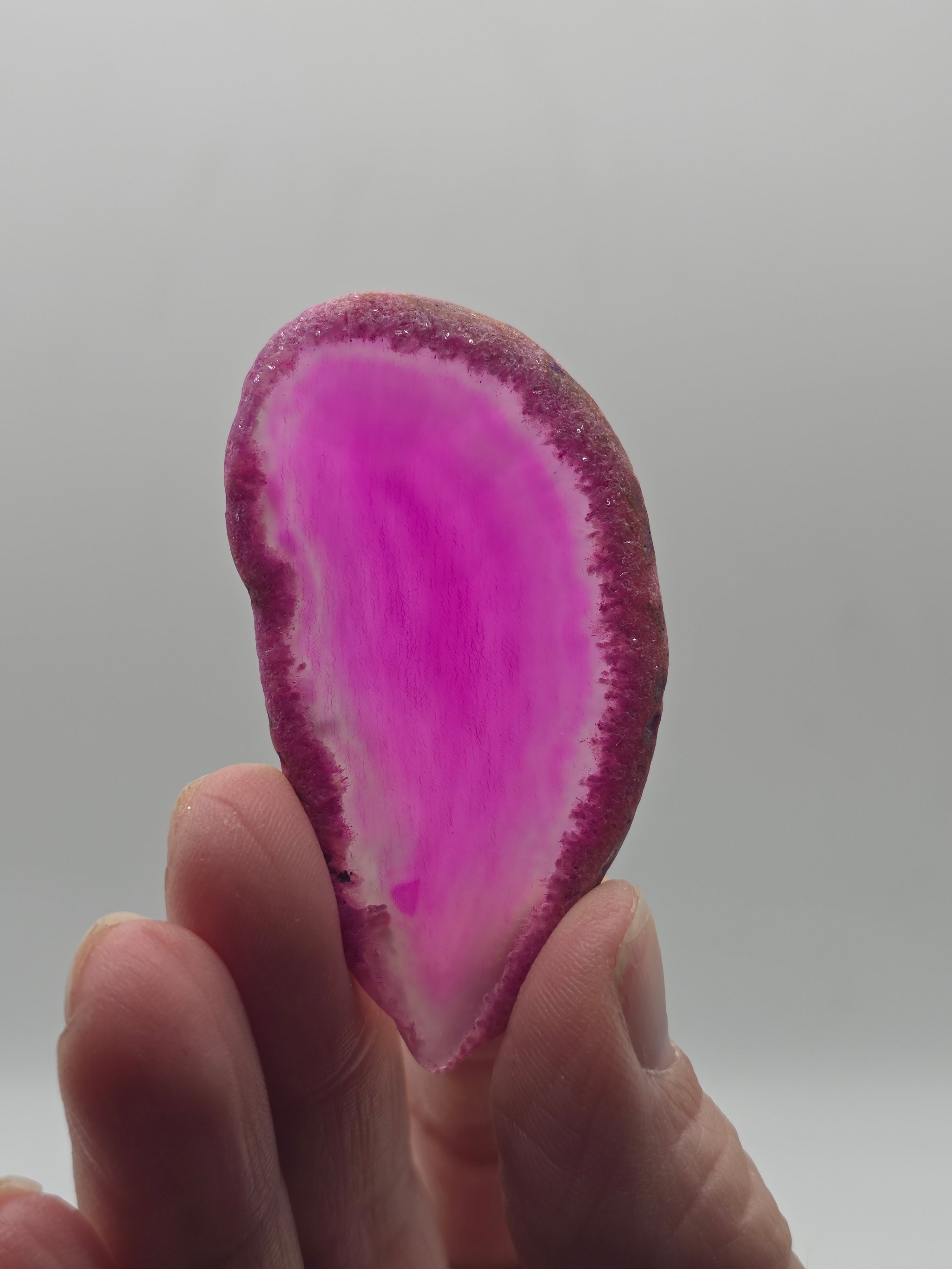Person holding a pink and white Agate crystal against a plain background