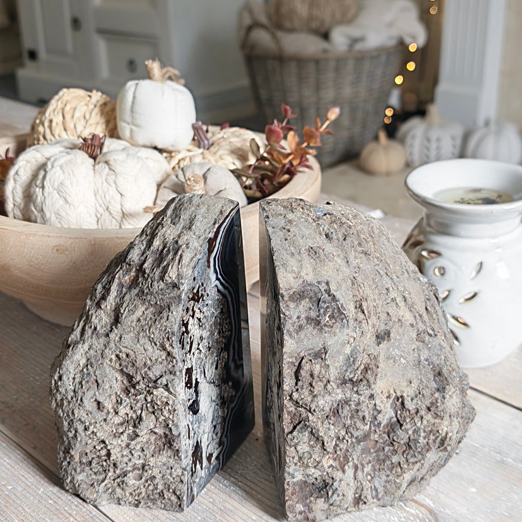 Two rustic gray stone bookends displayed on a light wood table in a cozy, styled home interior setting.