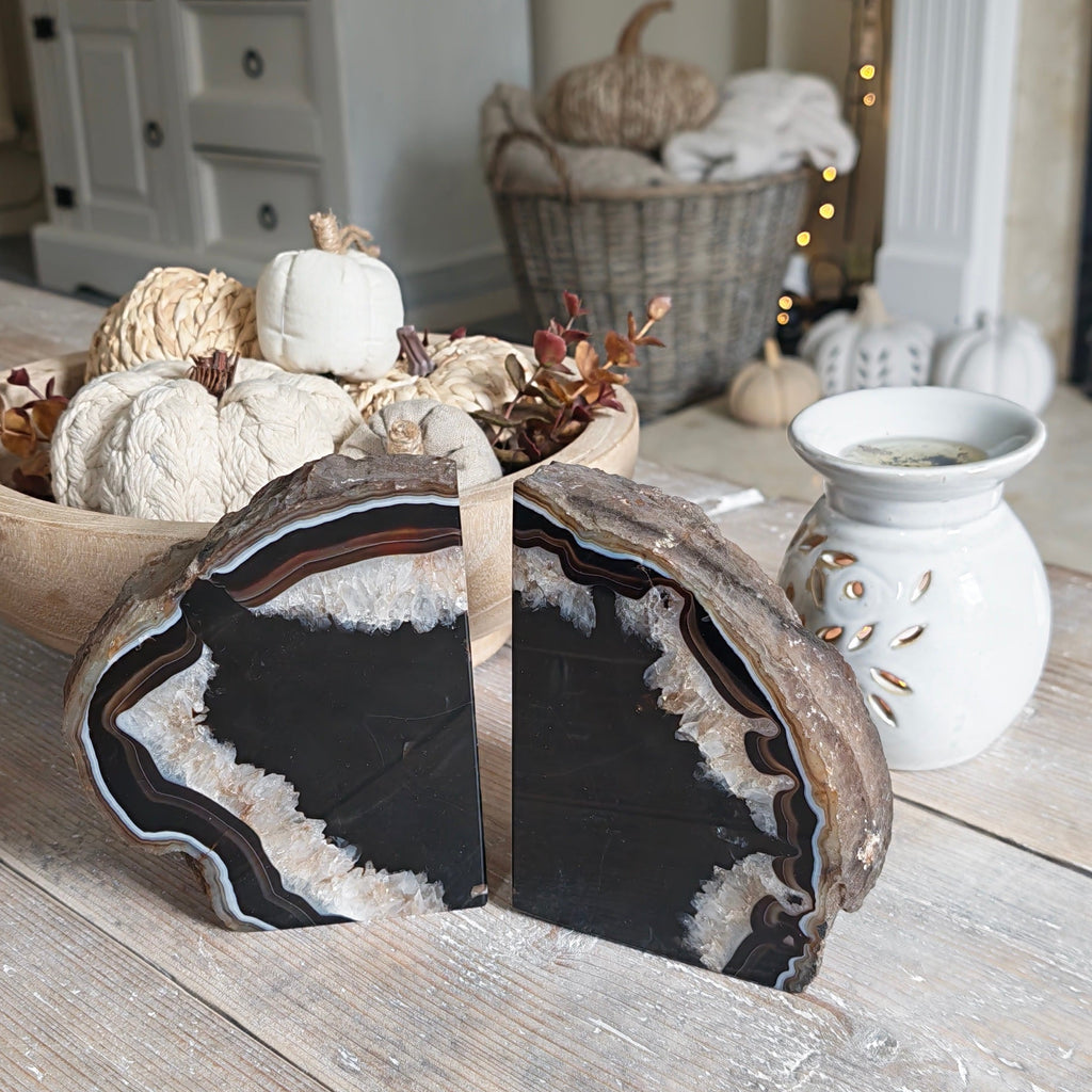 Two large decorative agate slice bookends with black, white, and brown natural patterns, displayed on a rustic wooden table in a styled home interior.