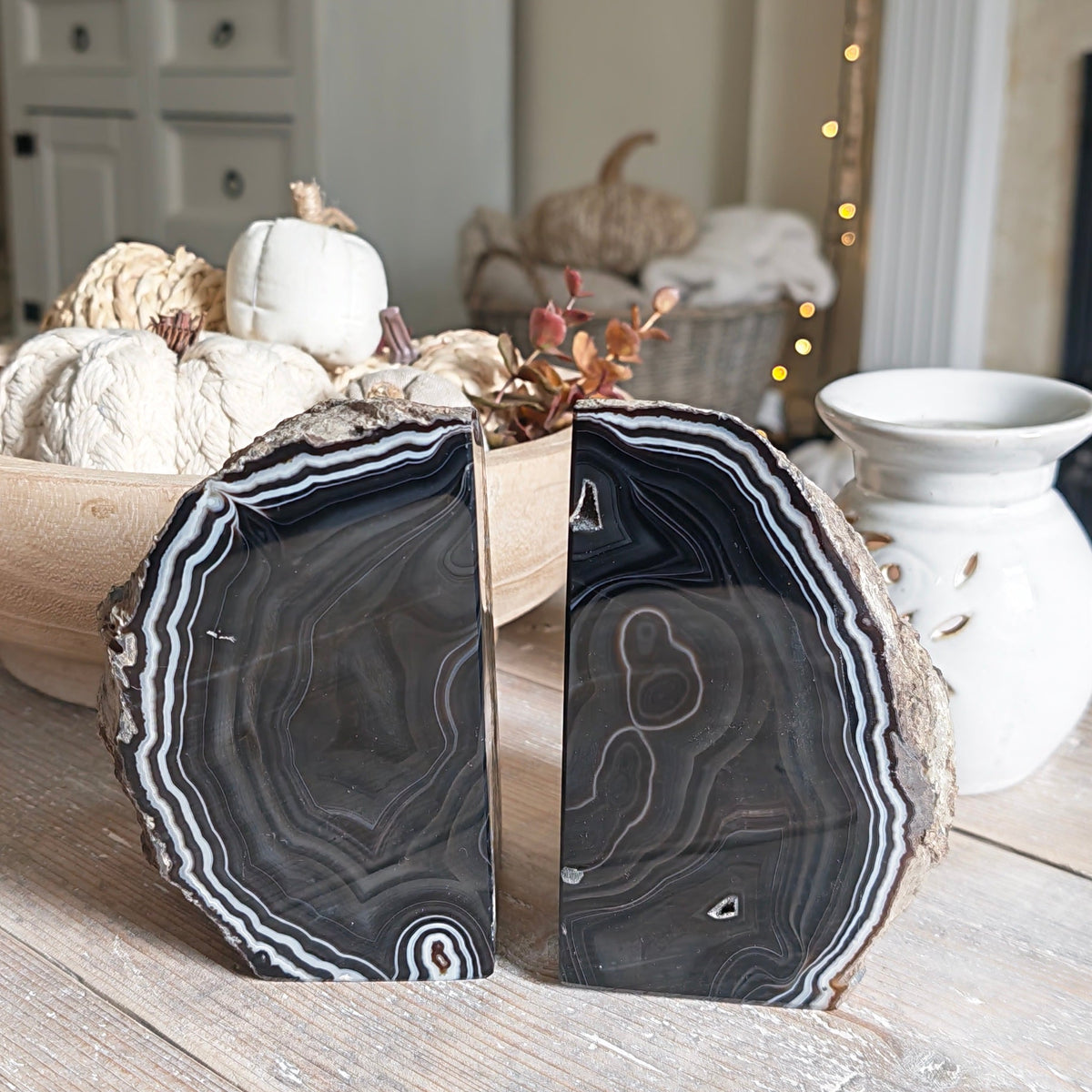 Two decorative black agate slice bookends with natural edges, displayed on a rustic wooden table in a cozy living room setting.