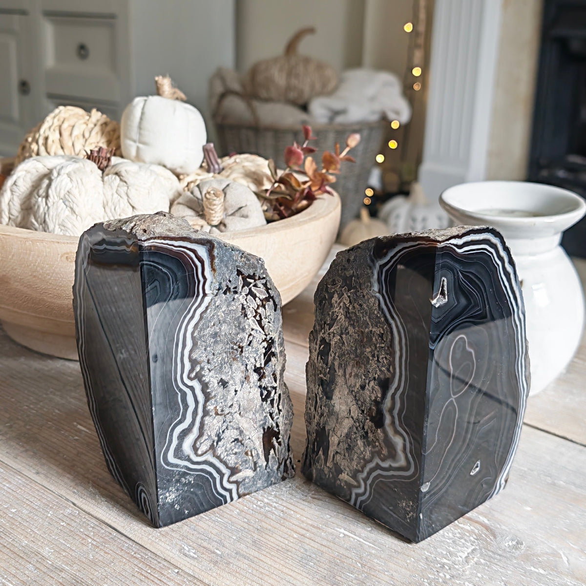 Two decorative black agate stone blocks with natural banding patterns, displayed on a rustic wooden table in a cozy, softly lit living room setting.