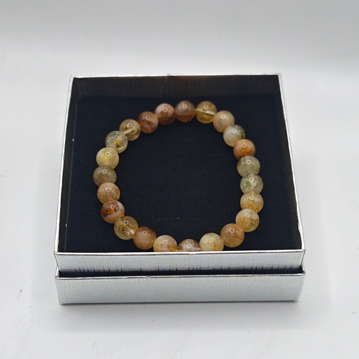 A premium citrine beaded bracelet displayed inside an open presentation box with a silver base on a  white background.