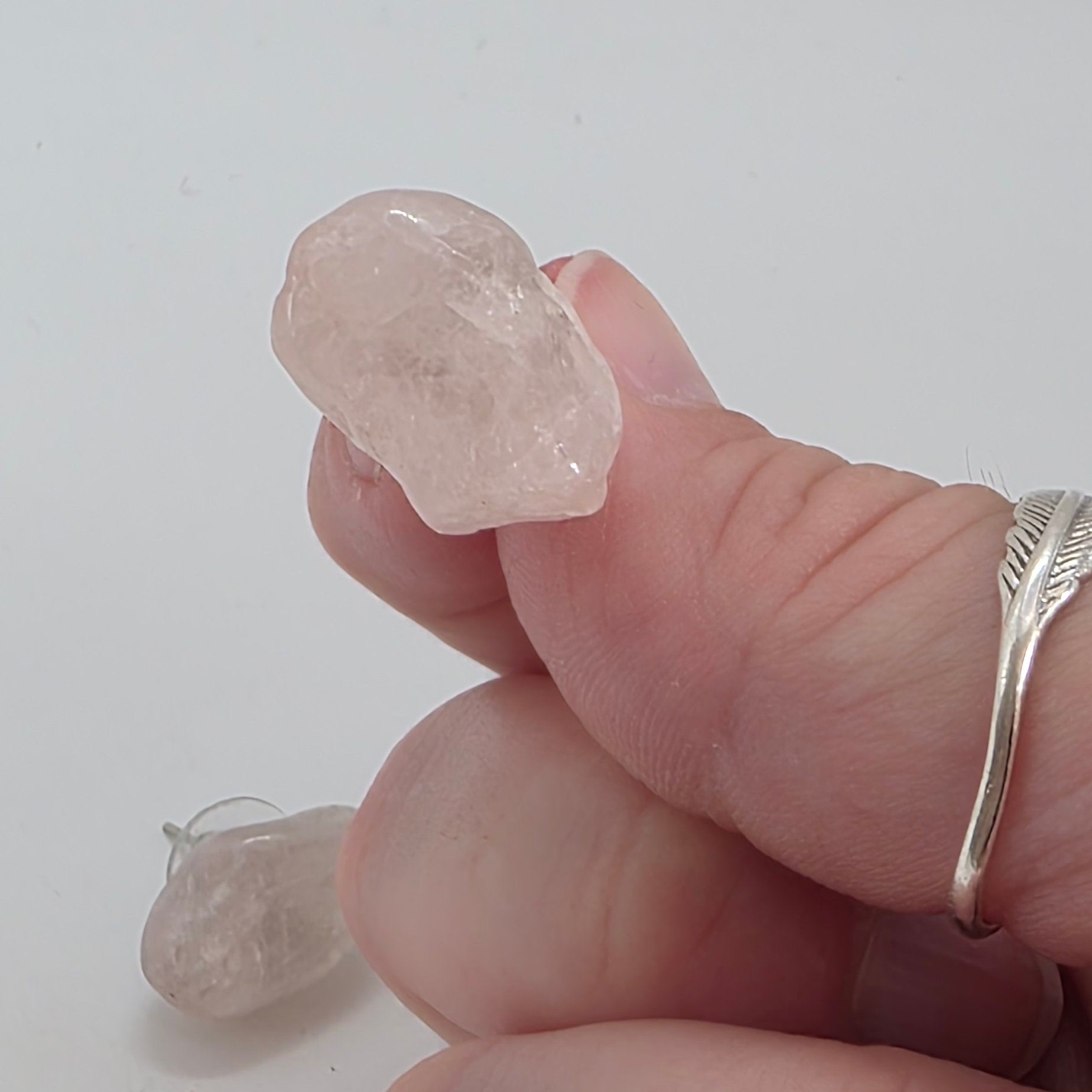 Hand holding a rose quartz Earring on a white background