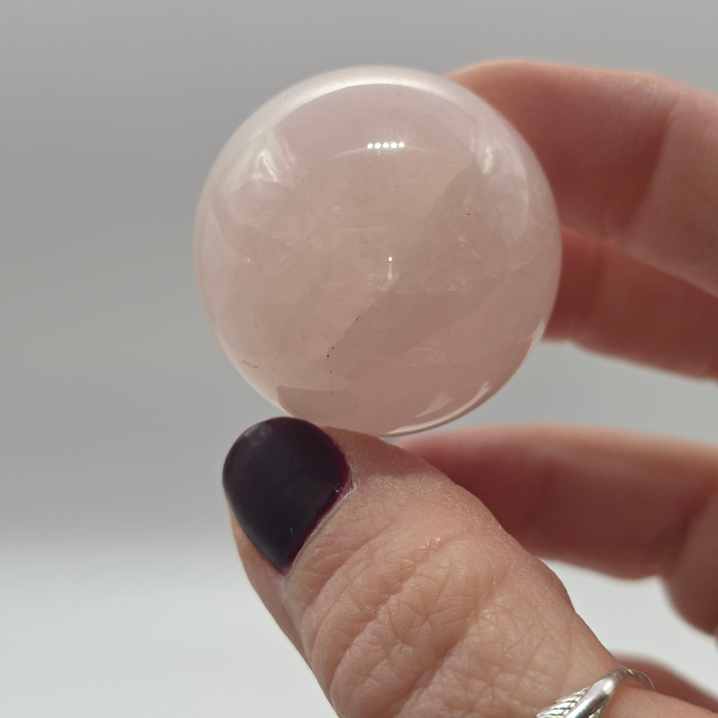 Rose quartz crystal ball held in a person's hand – polished gemstone sphere for emotional comfort
