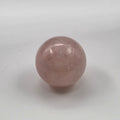 Rose quartz crystal ball on white background – polished sphere from Madagascar for self-love and heart healing