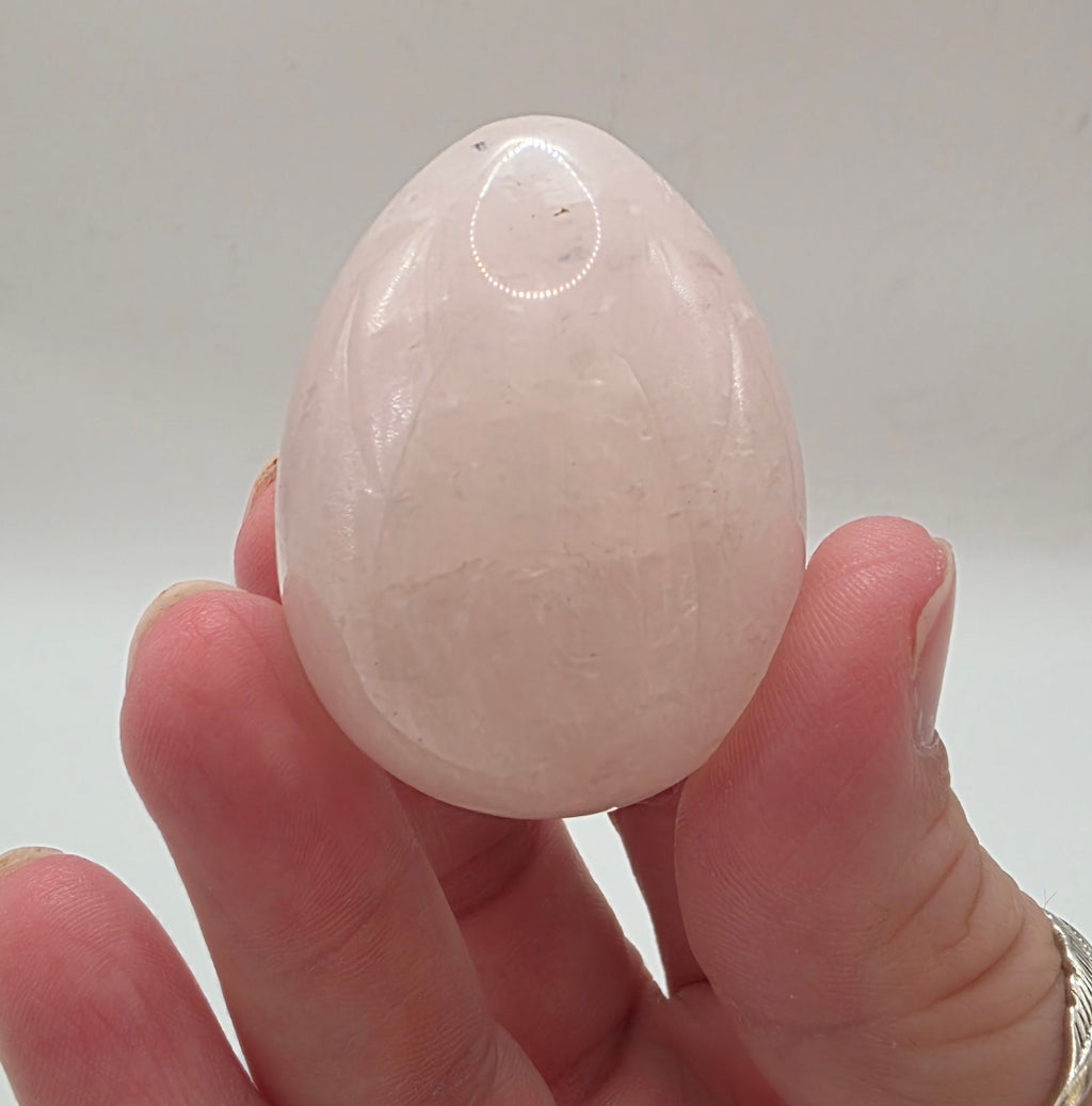 Rose quartz egg held in between fingers showing 45mm size