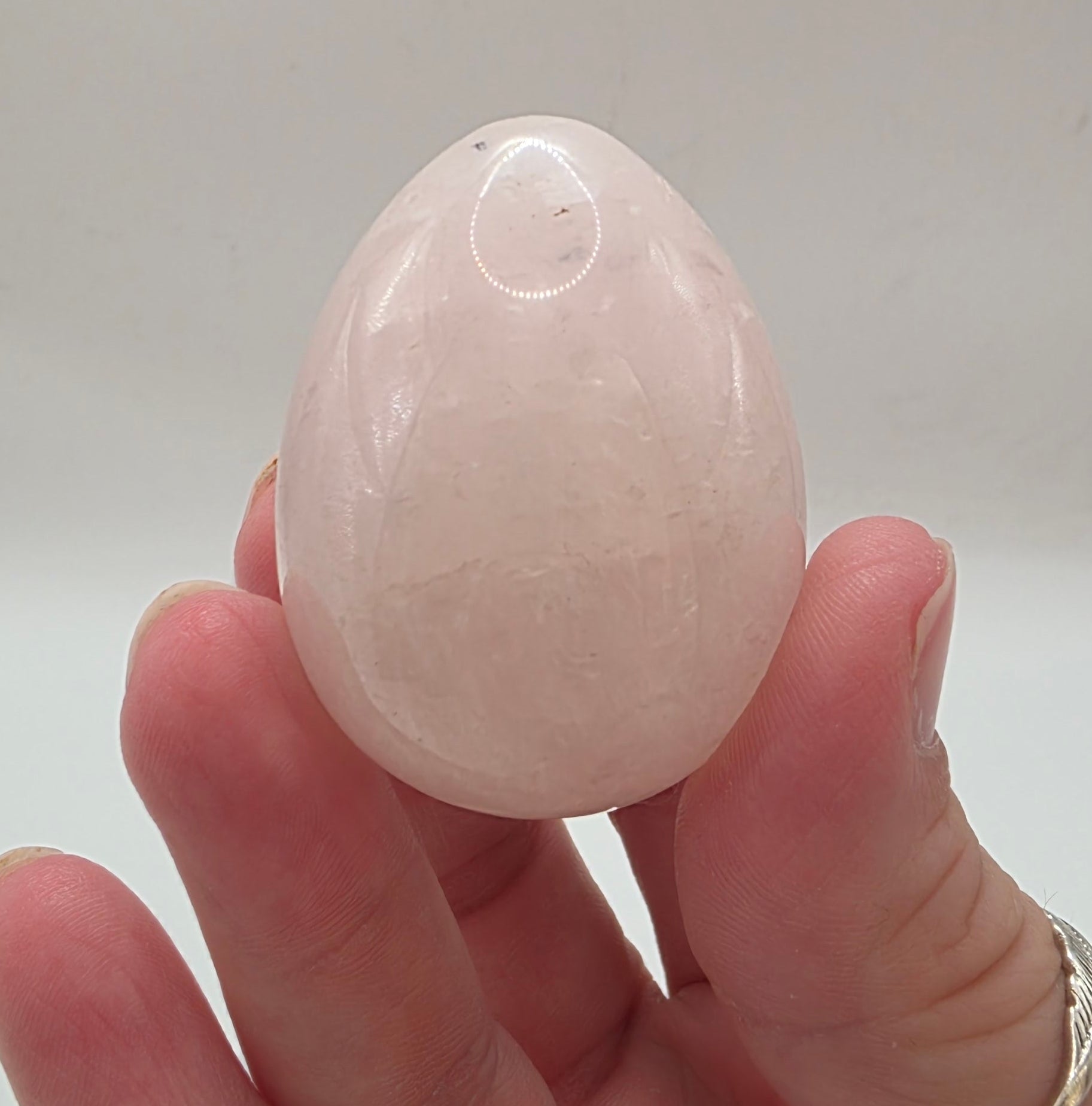 Rose quartz egg held in between fingers showing 45mm size