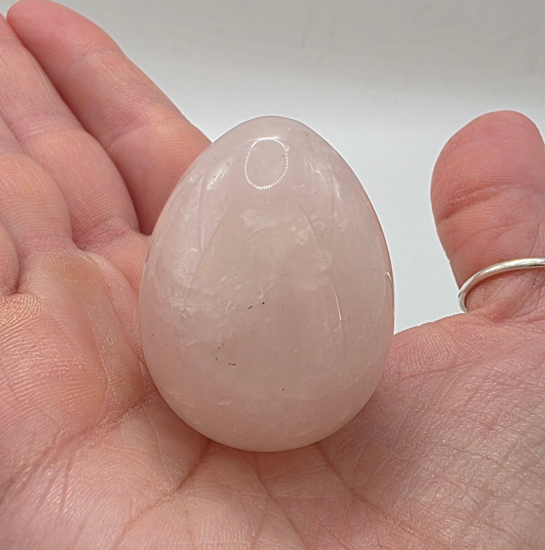 Rose quartz egg held in palm showing 45mm size
