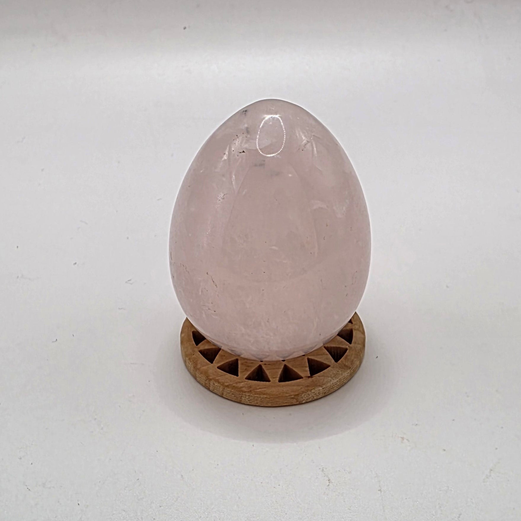 Polished 45mm rose quartz crystal egg on white background