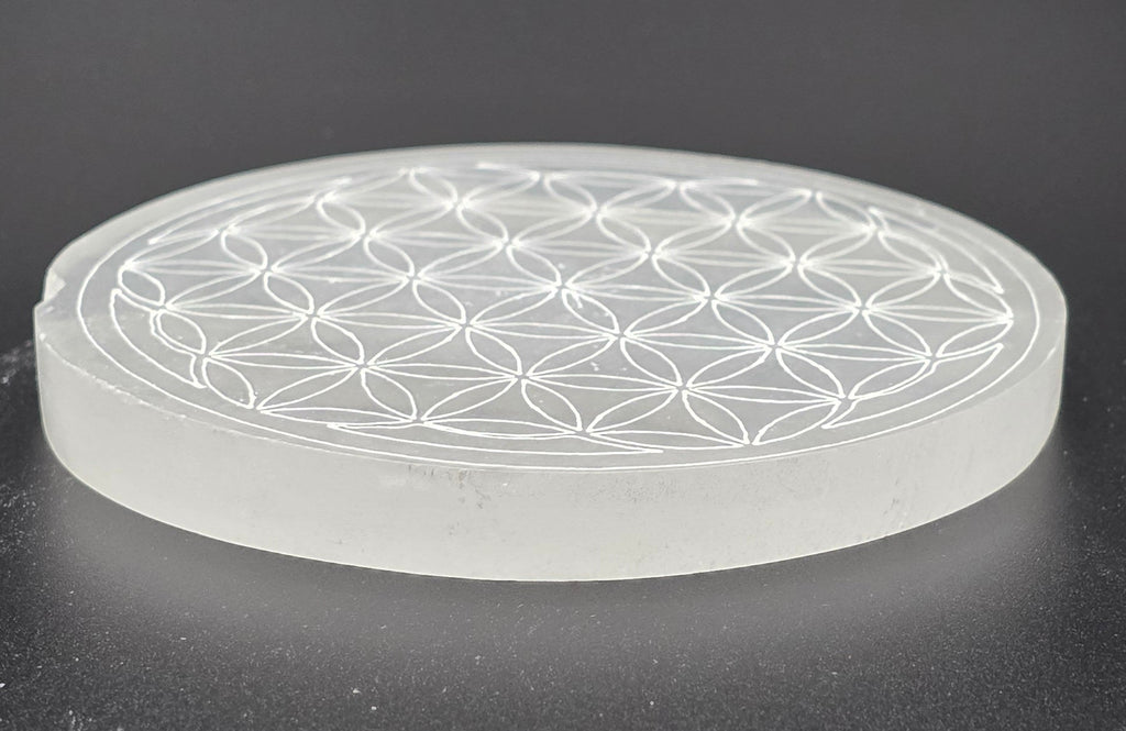 Close up of selenite charging plate showing Flower of Life sacred geometry engraving – natural white selenite