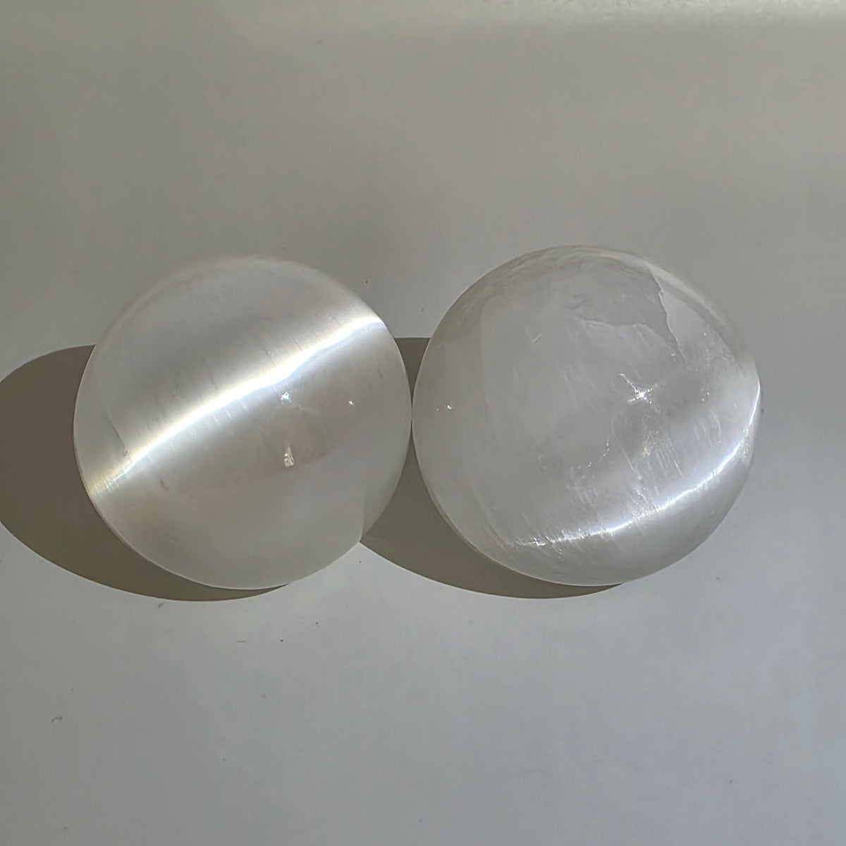 2 Selenite crystal balls 5cm on white background – white satin spar sphere for energy cleansing