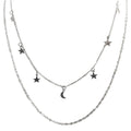 Layered silver necklace with star and moon pendants on a white background
