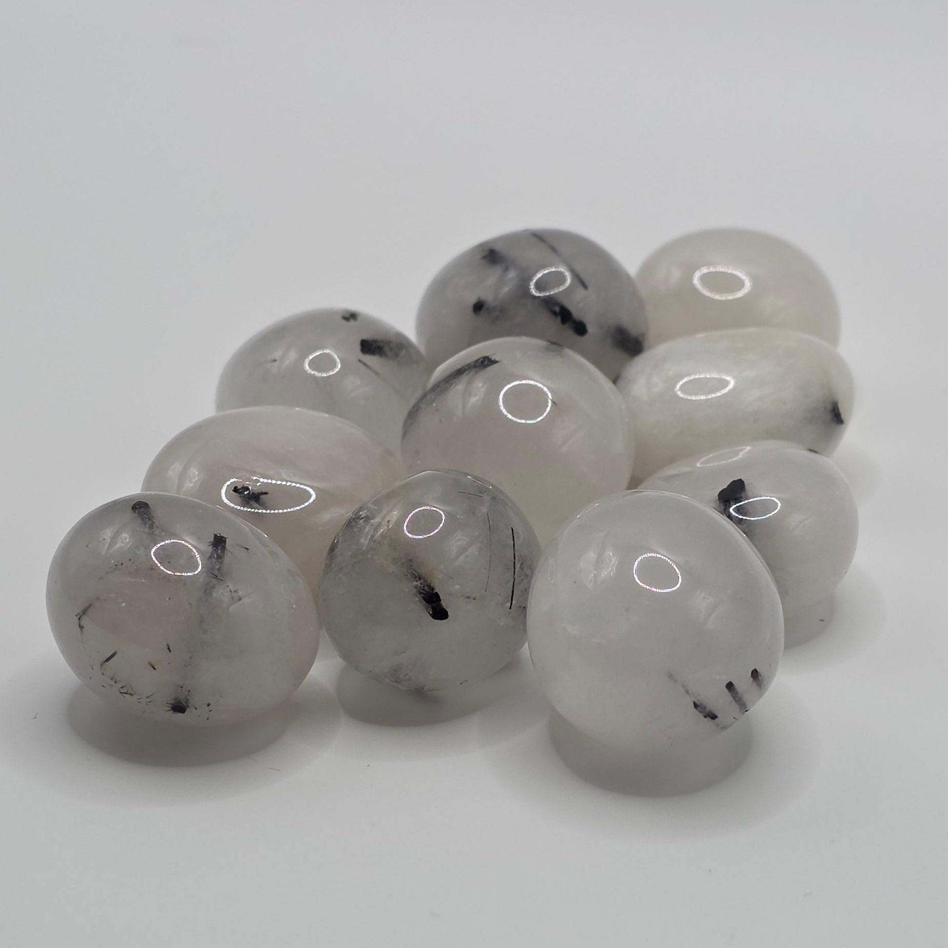 Group of Tourmaline in quartz tumbled stones on white background – clear quartz with black tourmaline needles – 2-3cm polished stone