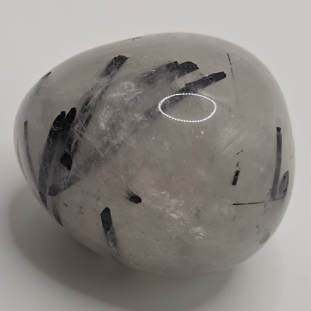Tourmaline in quartz tumbled stone on white background – clear quartz with black tourmaline needles – 2-3cm polished stone