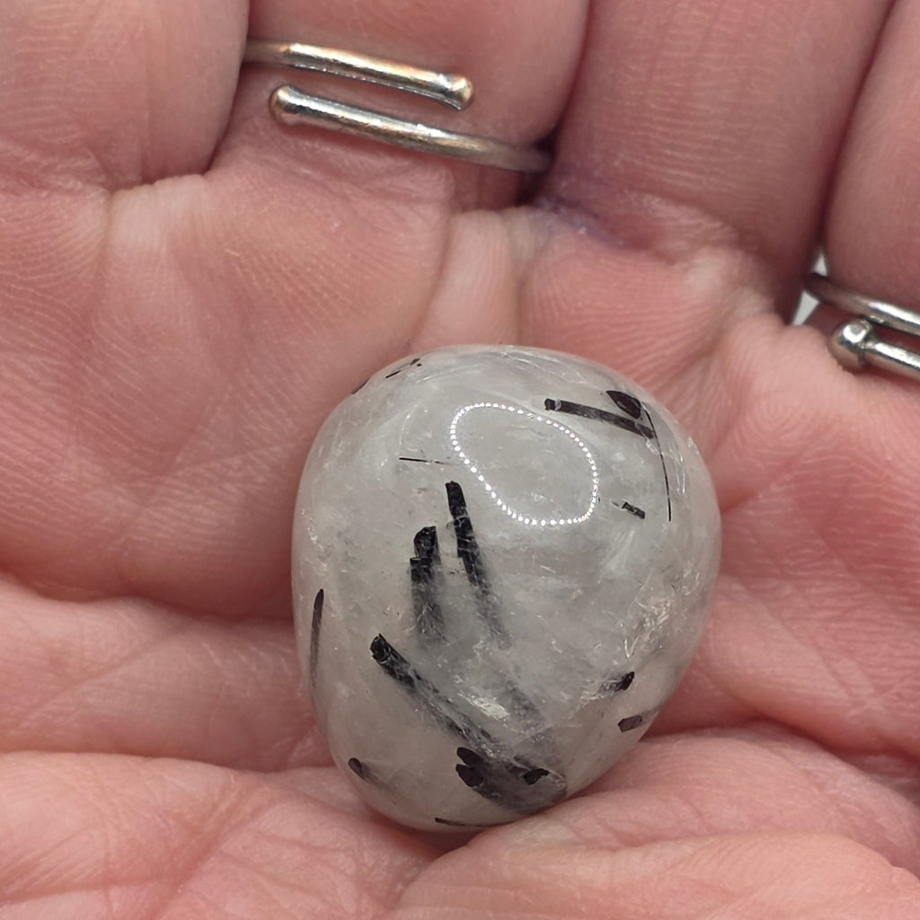 Tourmaline in quartz tumbled stone held in palm– clear quartz with black tourmaline needles – 2-3cm polished stone
