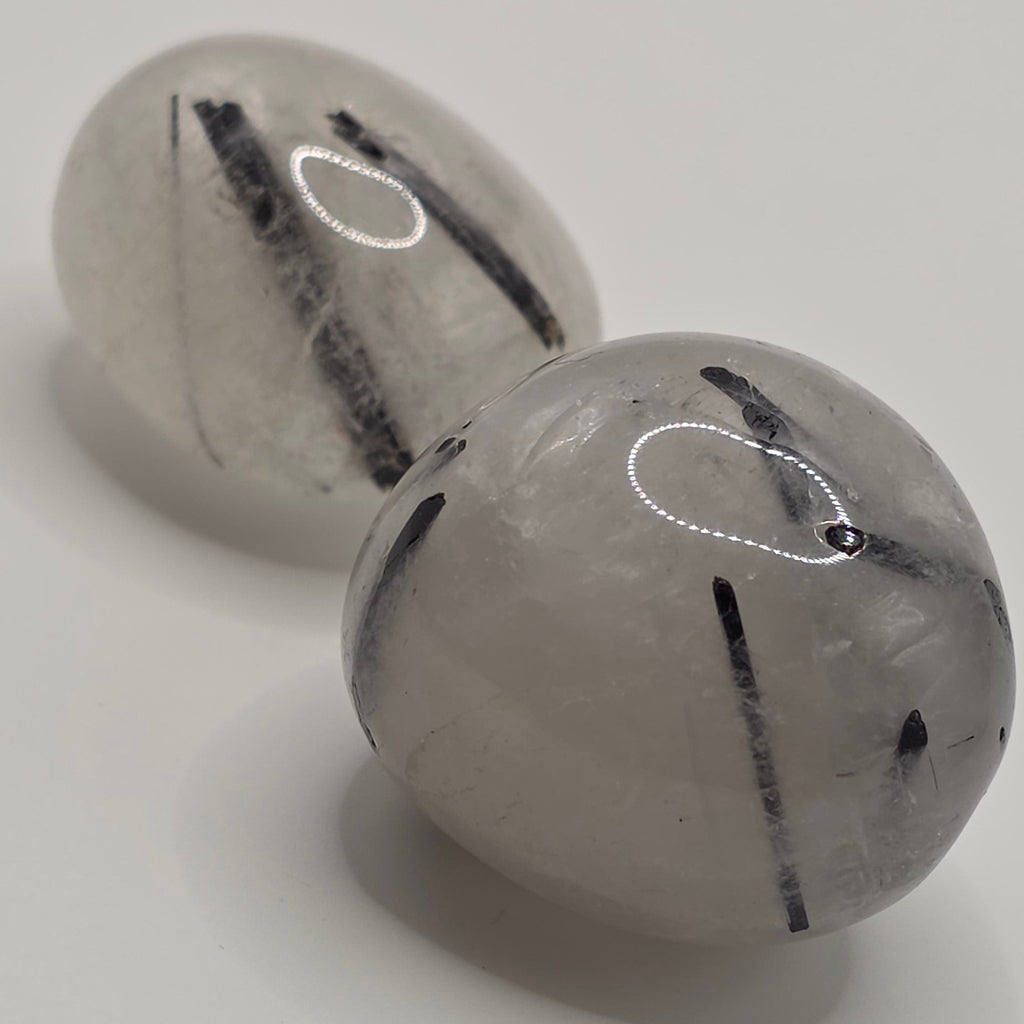 Pair of Tourmaline in quartz tumbled stones on white background – clear quartz with black tourmaline needles – 2-3cm polished stone