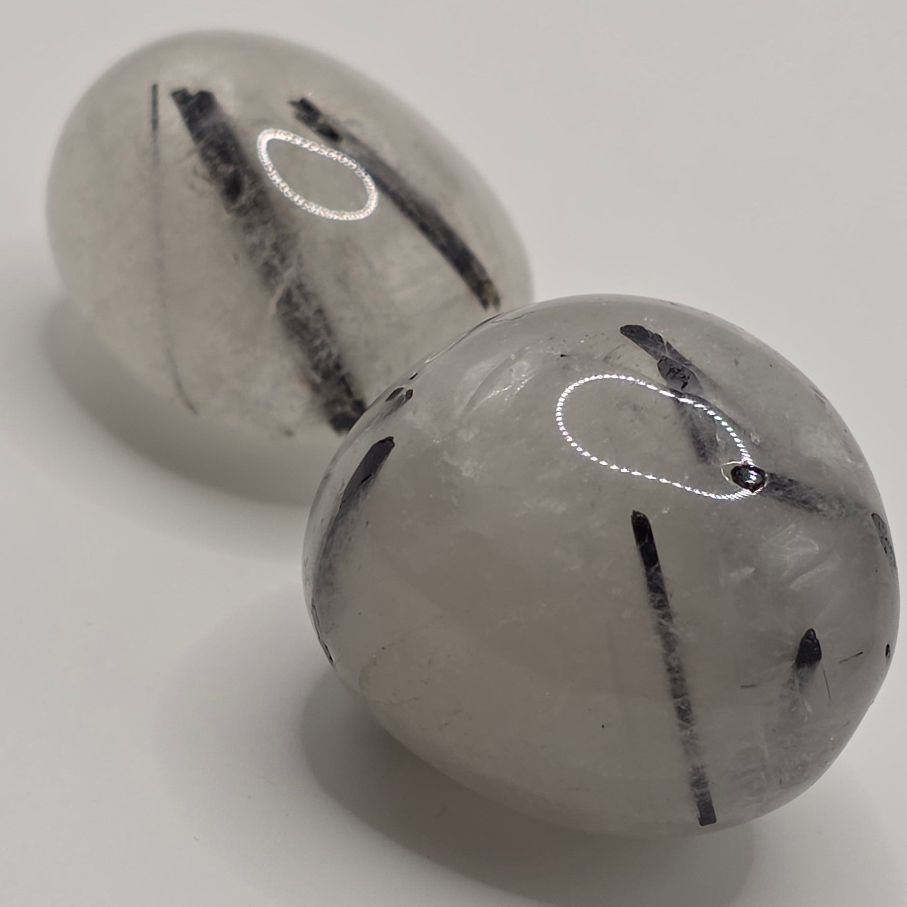 Pair of Tourmaline in quartz tumbled stones on white background – clear quartz with black tourmaline needles – 2-3cm polished stone