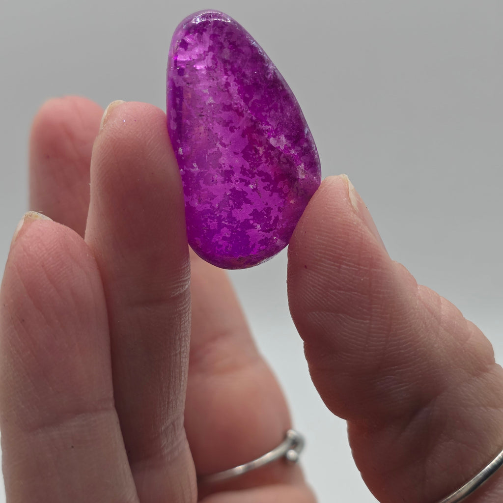 Witch aura tumbled stone held in a person's hand – magical aura quartz for protection and intuition