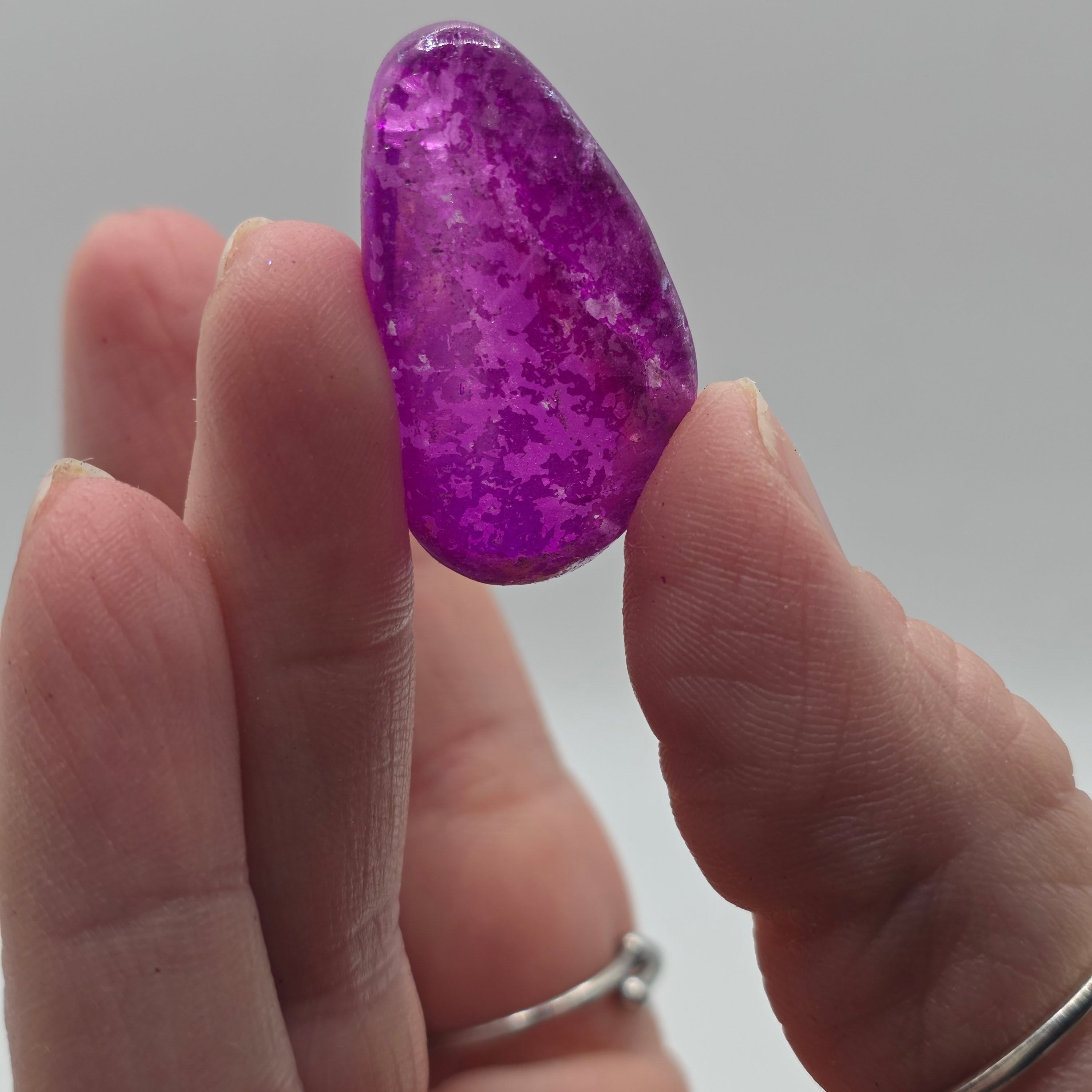 Witch aura tumbled stone held in a person's hand – magical aura quartz for protection and intuition